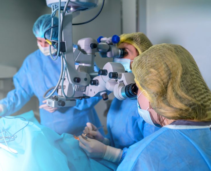 Blepharoplasty plastic surgery. Rejuvenation and modification of the area around the eyes. Plastic surgeon and nurses doing eyelid surgery on a female patient using a microscope